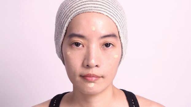 Asian girl or woman 40 years old beautiful face with japanese look making up by foundation liquid and cosmetic brush on sensitive skin for helping her complexion look flawless and real no retouch
