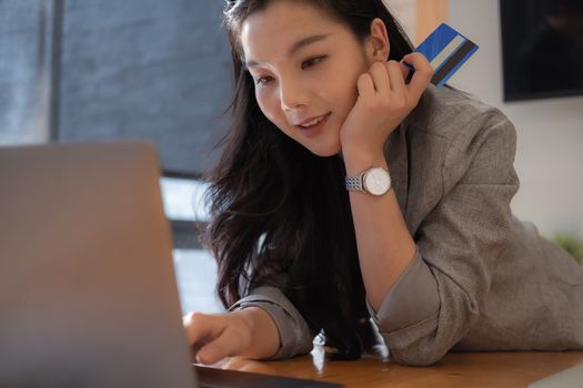 Asian woman makes a purchase on the Internet on the laptop computer with credit card.