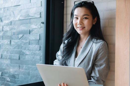 Portrait of smiling millennial businesswoman holding laptop computer looking at camera.