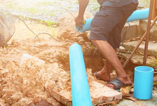 broken pipe in hole with water motion at roadside and plumber working repair