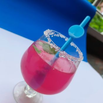 Colorful pink juice added with lemon juice and straw inside it plated beautifully in white and blue background and good for immunity booster