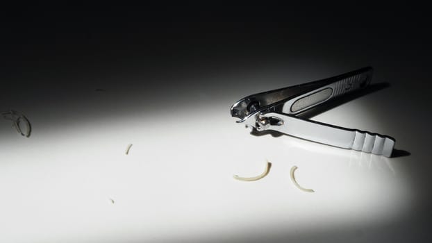 Close-up images of nail clipper from top view angle after cut out sensitive damage nails from hands and fingers and lay down on the floor and have sun light shade and shadow on it.