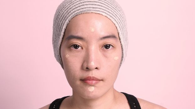 Asian girl or woman 40 years old beautiful face with japanese look making up by foundation liquid and cosmetic brush on sensitive skin for helping her complexion look flawless and no retouch.