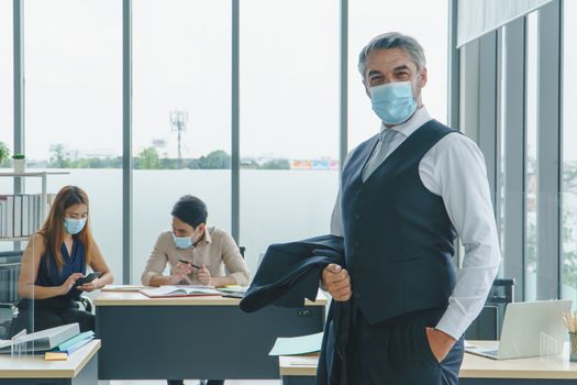 Business people wear a protective mask to work together in the company office. social distancing is the new normal. The concept of preventing the spread of coronavirus or COVID-19