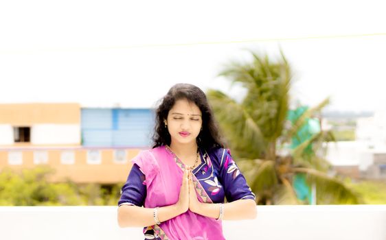 Beautiful Hindu young girl praying with folded hands and open air around