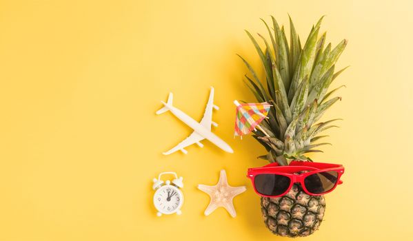 Celebrate Summer Pineapple Day Concept, Top view flat lay of funny fresh pineapple in sunglasses with model plane and starfish, in studio isolated on yellow background, Holiday summertime in tropical
