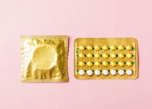 World sexual health or Aids day, condom in wrapper pack and contraceptive pills blister hormonal birth control pills, studio shot isolated on a pink background, Safe sex and reproductive health concept