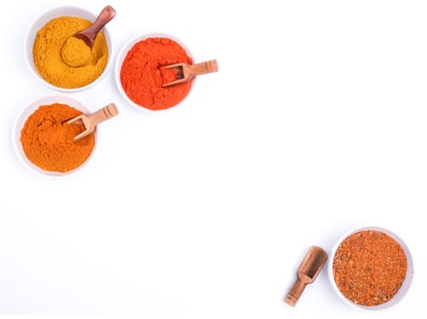 Colorful spices and wooden spoon in white bowl on white background