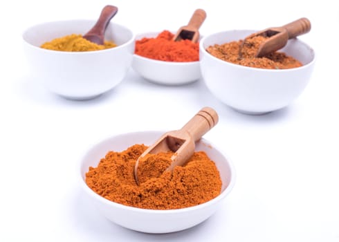 Colorful spices and wooden spoon in white bowl on white background