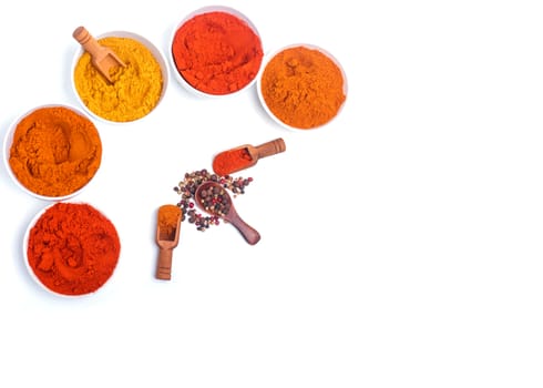 Colorful spices in wooden spoon and white bowl on white background