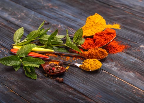Colorful spices and wooden spoon on black background