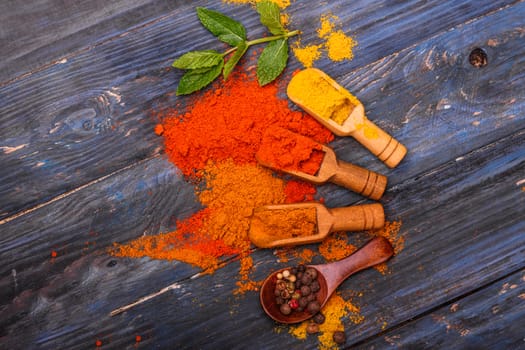 Colorful spices and wooden spoon on black background