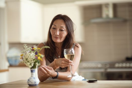 An Asian woman having a drink in a kitchen