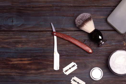 Razor, brush, perfume, balsam and shaving foam on a black background.