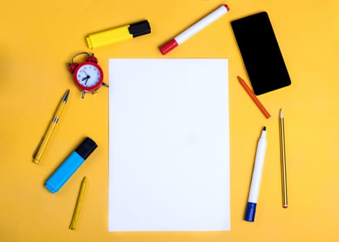 Empty paper, pencils, cloak, phone, highlighters on yellow background