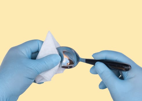 man in protective gloves holding and cleaning spoon