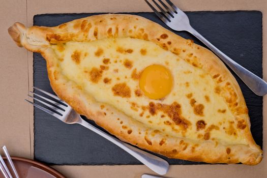 Georgian dish khachapuri with egg in the center. Soft focus. Closeup. Top view.