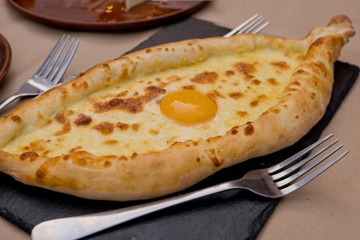 Georgian dish khachapuri with egg in the center. Soft focus. Closeup.