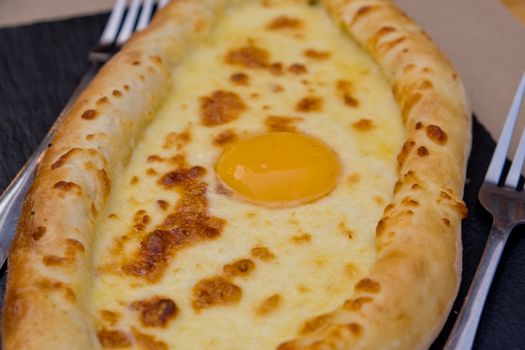 Georgian dish khachapuri with egg in the center. Soft focus. Closeup.