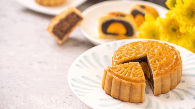 Tasty baked egg yolk pastry moon cake for Mid-Autumn Festival on bright cement table background. Chinese traditional food concept, close up, copy space.