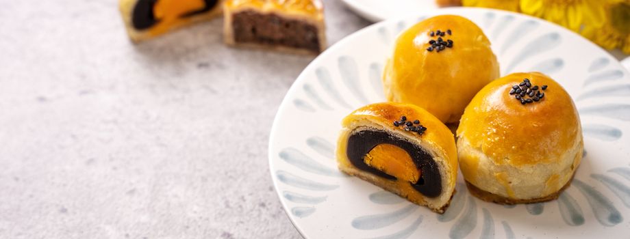 Tasty baked egg yolk pastry moon cake for Mid-Autumn Festival on bright cement table background. Chinese traditional food concept, close up, copy space.