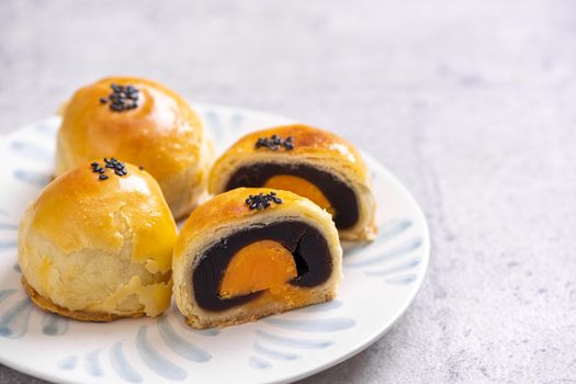 Tasty baked egg yolk pastry moon cake for Mid-Autumn Festival on bright cement table background. Chinese traditional food concept, close up, copy space.