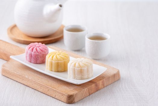 Colorful snow skin moon cake, sweet snowy mooncake, traditional savory dessert for Mid-Autumn Festival on bright wooden background, close up, lifestyle.