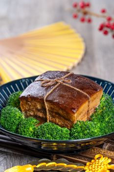 Dong Po Rou (Dongpo pork meat) in a beautiful blue plate with green broccoli vegetable, traditional festive food for Chinese new year cuisine meal, close up.