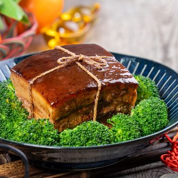 Dong Po Rou (Dongpo pork meat) in a beautiful blue plate with green broccoli vegetable, traditional festive food for Chinese new year cuisine meal, close up.
