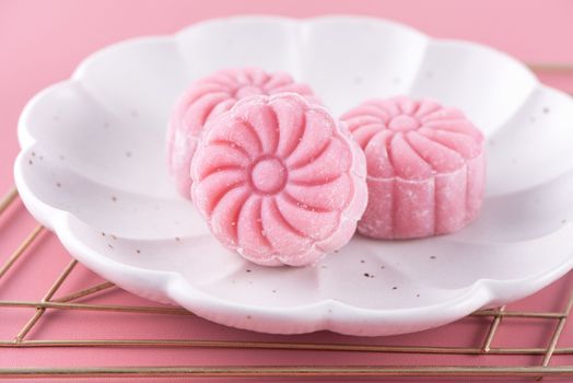 Colorful snow skin moon cake, sweet snowy mooncake, traditional savory dessert for Mid-Autumn Festival on pastel pale pink background, close up, lifestyle.