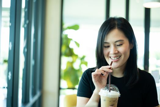 An Asian beautiful woman has drinking an ice cappuccino in the morning.