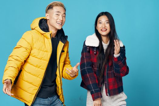 Cheerful young people on isolated background advertise warm clothes and laugh at the camera