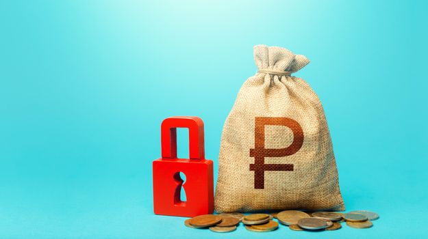 Russian ruble money bag and red padlock. Blocking bank accounts and seizing assets. Cash flow monitoring. Tight government control over the financial system. Freezing of pension savings.