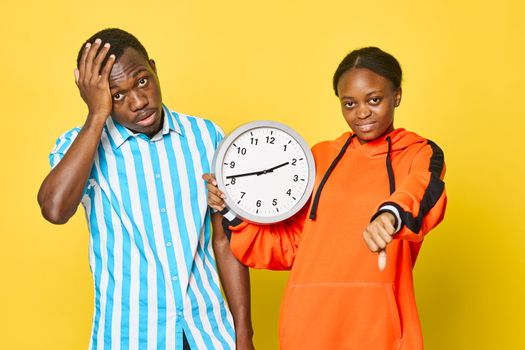 A man and woman of African appearance with a round clock in their hands