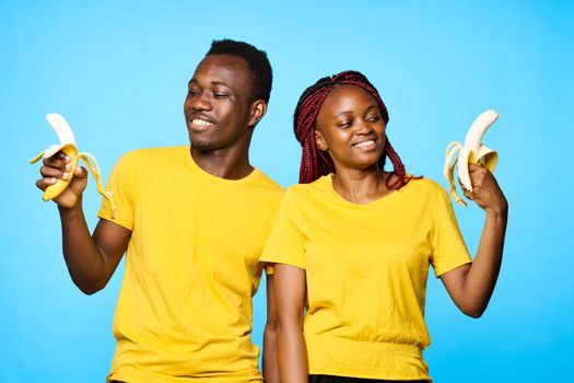 man and woman of African appearance with bananas in hands smiling on isolated background