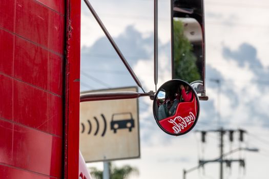Coca cola company logo image. reflected in the rear view mirror of a delivery truck. urban scene