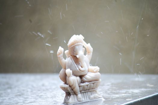 shot of hindu god Ganesha with the heavy tropical monsoon rain drops falling on him showing the prosperity and bountiful harvest from the lords blessings. Ganesh and new beginnings in Hinduism