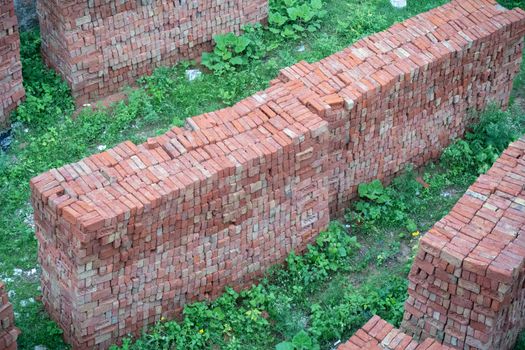 shot of bricks placed in high ordered piles on grass ready for the construction of property, real estate, offices, homes and shopping malls as India grows and infrastructure develops