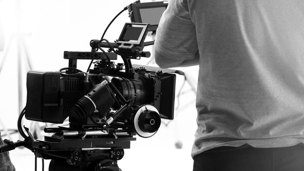 Behind video camera that recording online commercial or web film movie in the big studio production with professional equipment such as high resolution cam and monitors and LED light with crew team set