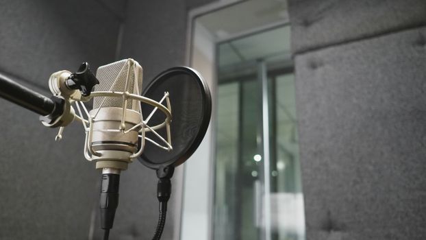 Studio microphone or mic for recording for vocal singer or commercial announcer with shock mount and pop filter on professional tripod in acoustic foam room for best sound and mix process