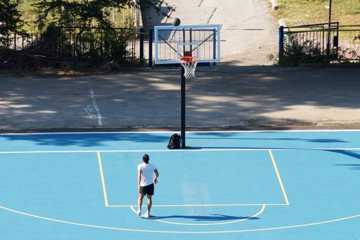 Varna, Bulgaria - August, 22, 2020: young man training with a ball on an outdoor basketball court