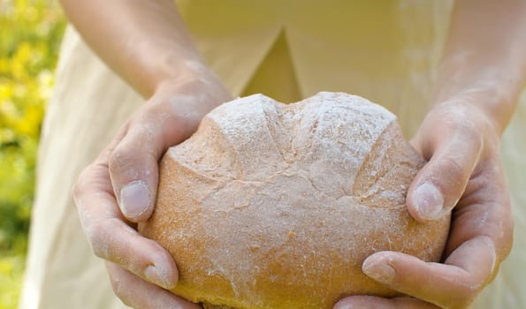 Close up homemade bread in female hands in the garden at summer. Natural organic handmade food