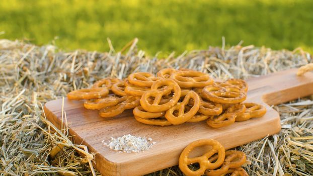 Close up pretzels on wooden cutting board outdoors on green natural background. Healthy natural food