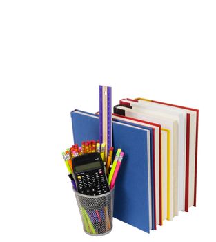 Vertical shot of a row of colorful books with the pages facing out and a wire pencil holder full of pencils, a ruler, and a calculator.  White background.  Copy space.