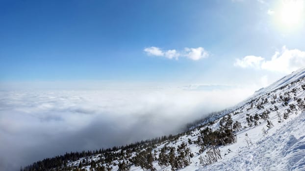 View from the snow covered mountain in winter to temperature inversion forming sea of clouds seen from above.