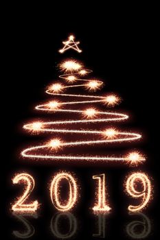 2019 and Christmas tree written with Sparkle firework on black background, happy new year concept