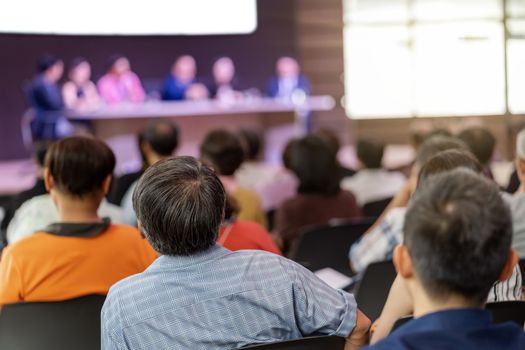 Rear view of Audience in the conference hall or seminar meeting which have Speakers are Brainstorming and talking on the stage, business and education about investment concept