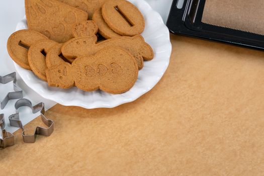 Young woman is decorating Christmas Gingerbread House cookies biscuit at home with frosting topping in icing bag, close up, lifestyle.