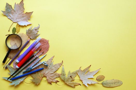 school stationery and autumn leaves on a yellow background, copy space, mockup blank.
