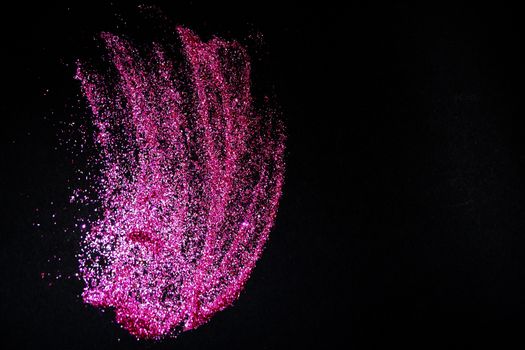 scattering of dark pink shiny glitter on a black background, copy space,